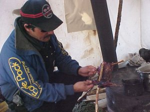 Harold Frost roasting a muskrat on a willow.